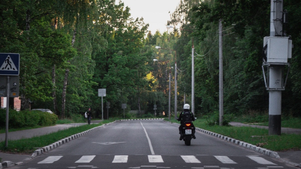 Person riding a motorcycle in a rural area of a town